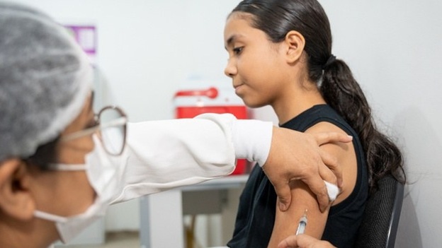 Profissional de saúde aplica vacina no braço de uma adolescente